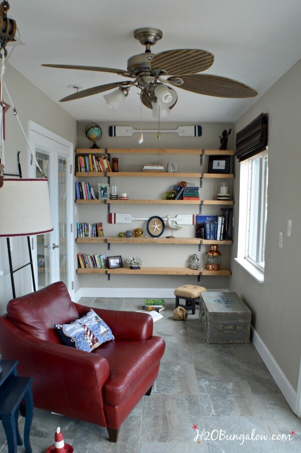 A narrow awkward space in a room with open shelving and a cozy red leather reading chair and light.