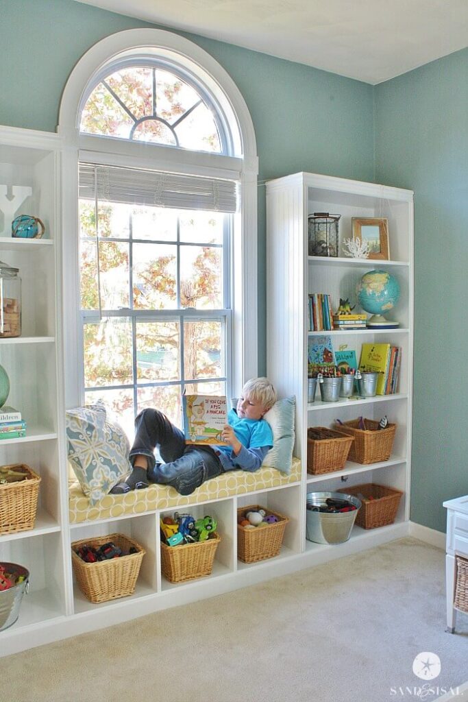 A simple reading nook ideas with ready to assemble white book shelves and bench forming a cozy window seat reading nook.
