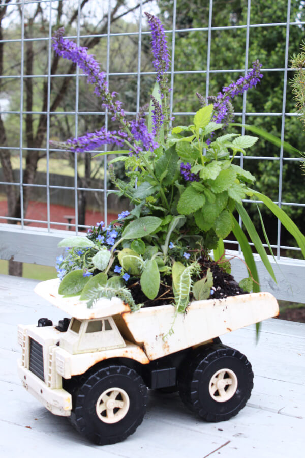 An old Tonka truck is turned into a planter container with potting soil and flowers. A cute planter container ideas.