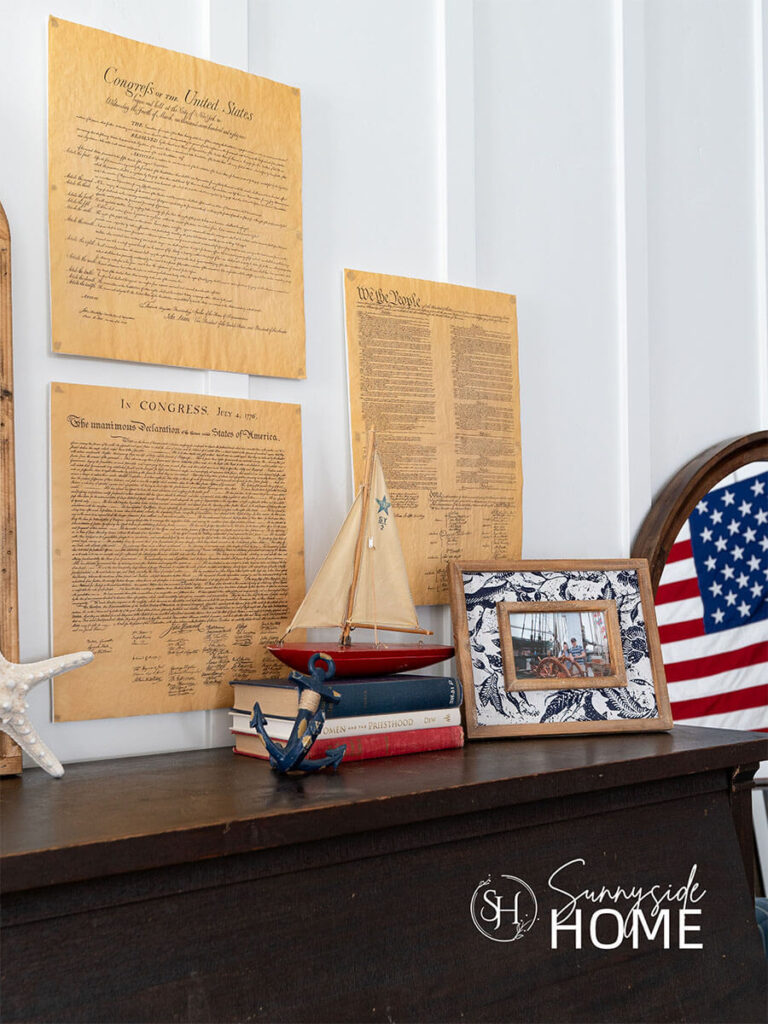Patriotic documents printing on vellum mounted above the piano and styled with a stack of red, white and blue books topped with a red sailboat.