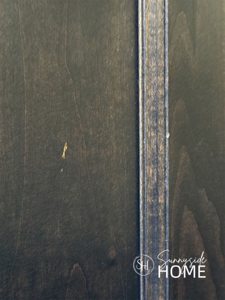 Dark stained Kitchen cabinet door with chips that need fixing.