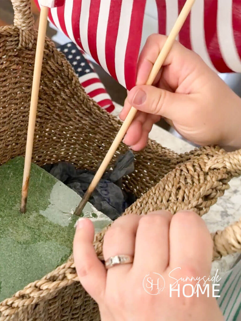 Woman places American flags into styrofoam inside a thrift store basket.
