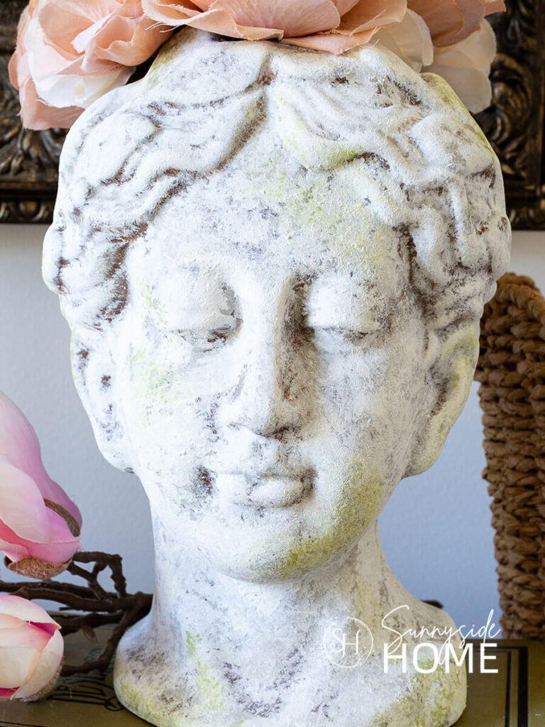 Textured head vase with layers of paint created an old world finish styled with florals on a book stack.