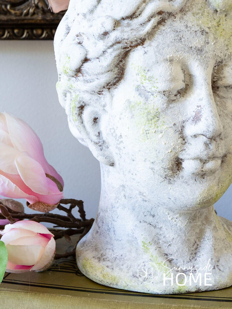 Textured head vase with layers of paint created an old world finish styled with florals on a book stack.