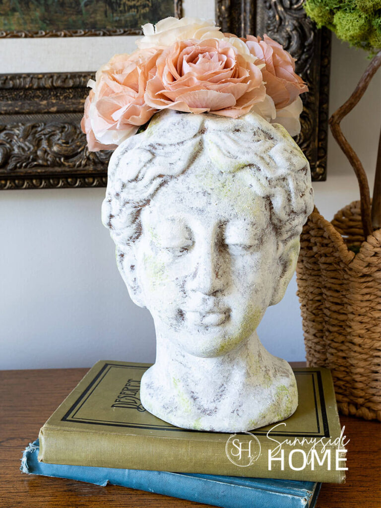 Old world texture finish on a vase styled with roses, on a book stack and a topiary.