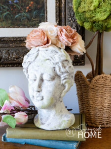 Old world texture finish on a vase styled with roses, on a book stack and a topiary.