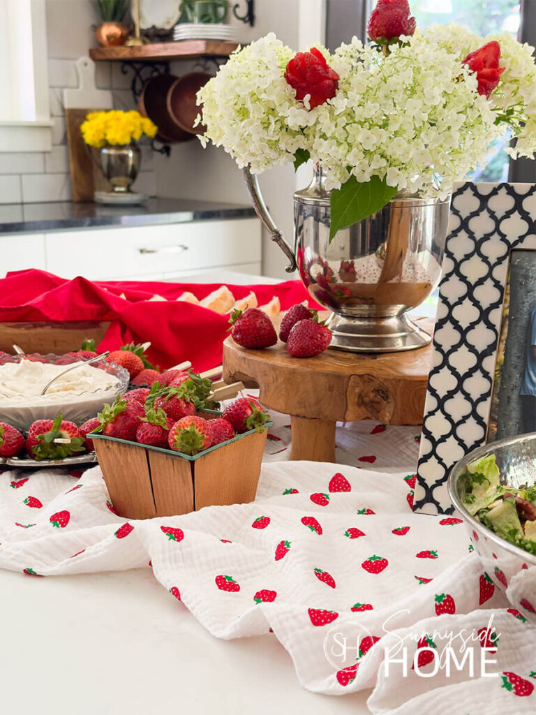 White hydrangea and strawberry centerpiece with a strawberry table runner. for a berry in love bridal shower ideas.
