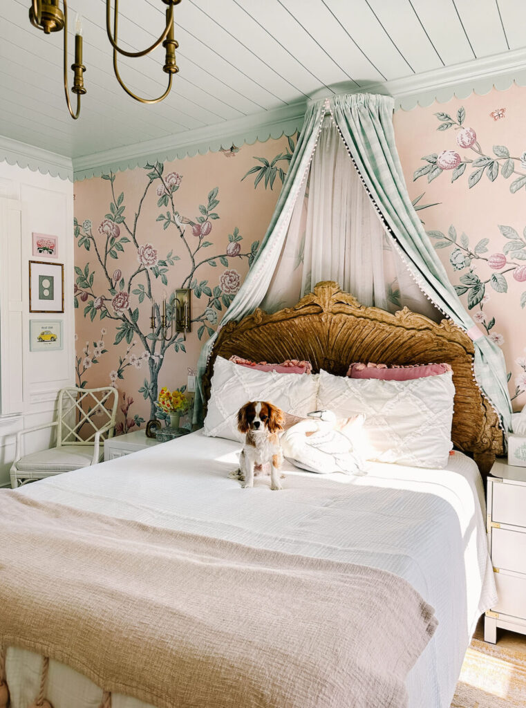 Scallop trim is added to crown moulding and painted the same color as the ceiling for a charming cottage look in a bedroom with a bed canopy, floral wallpaper.