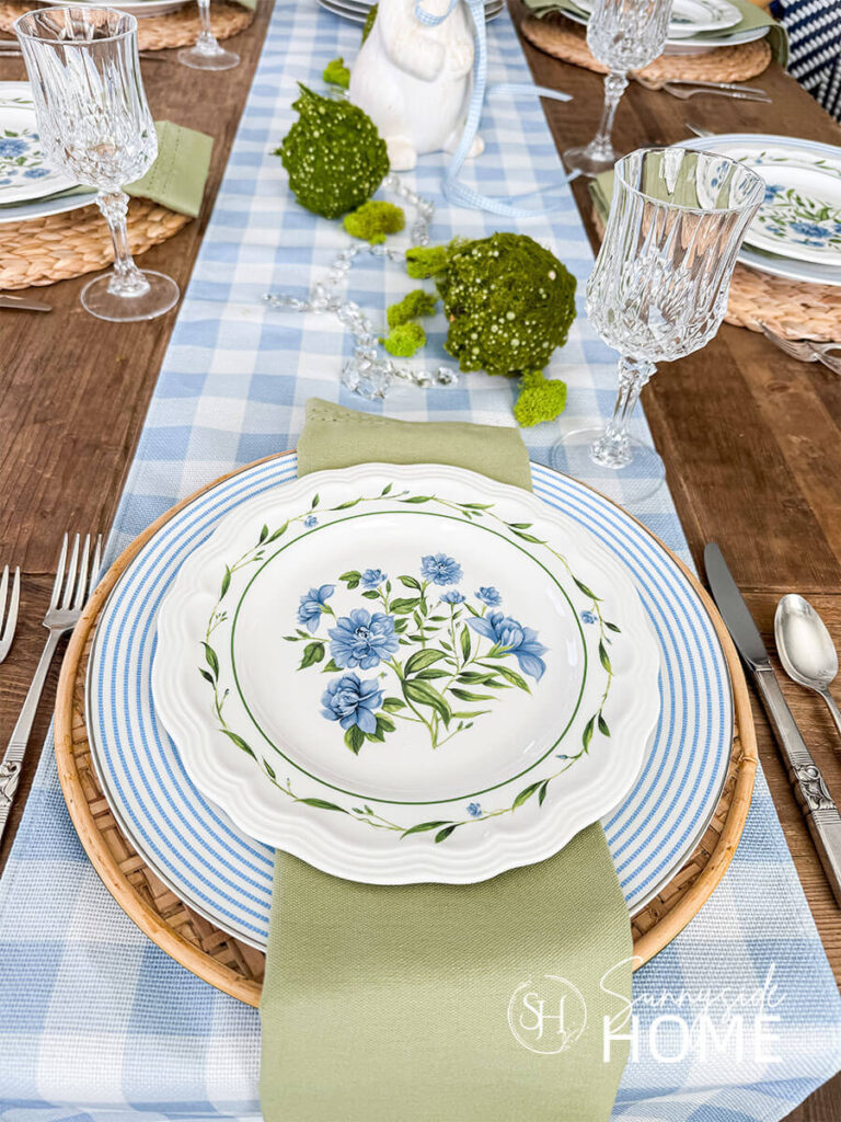 Pretty blue and white striped plates are placed on a rattan charger with a blue floral plate for a pretty spring tablescape.