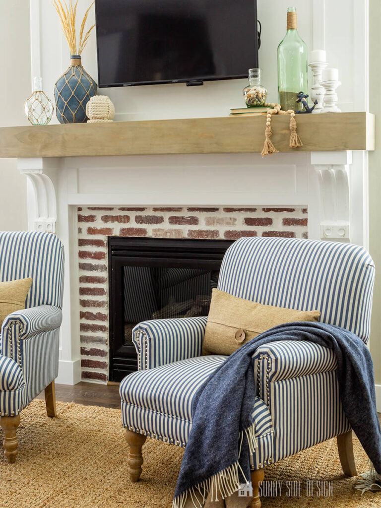 A pair of blue and white striped chairs styled in front of the fireplace.