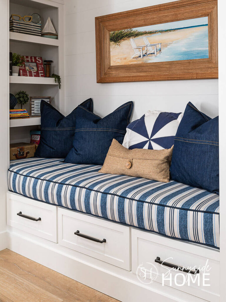 Reading nook with built in shelves and a blue and white striped cushion with denim, blue and white linen pillows