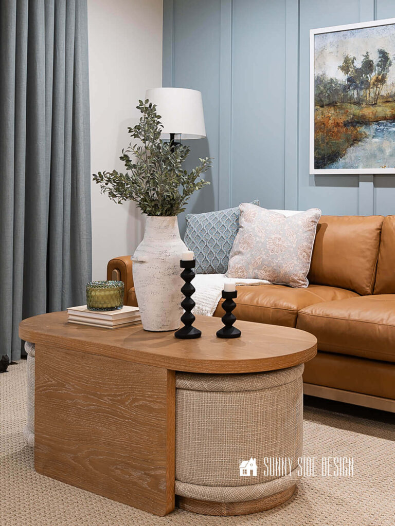 Blue board and batten accent wall, styled with leather furniture, oak coffee table with ottomans, blue curtains and accessories.
