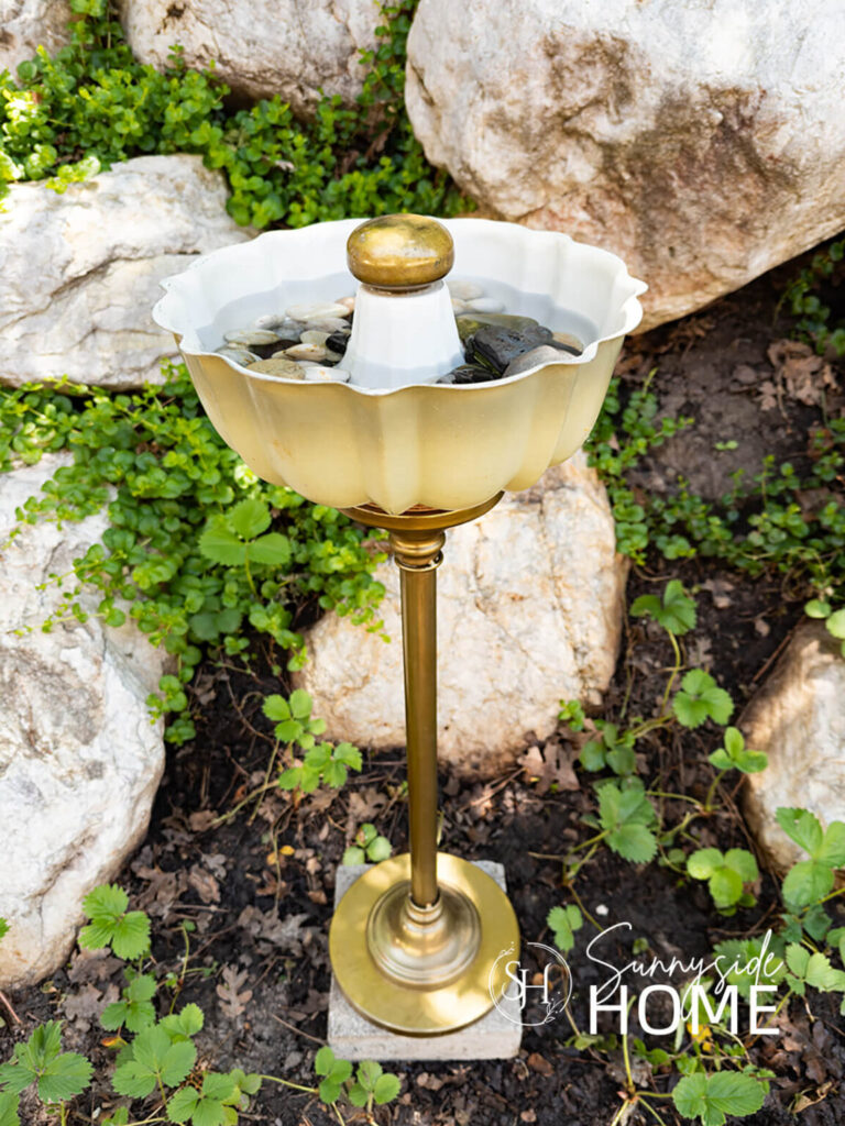 An old bundt pan and a table base are repurposed into a unique bird bath.