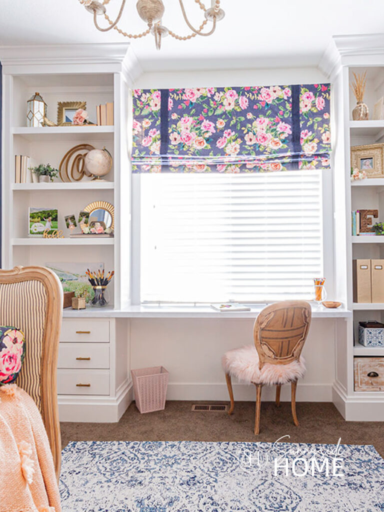 A blue and white Roman shade with pops of pink adds not only color, pattern and texture, but also provides light control in a girls bedroom.