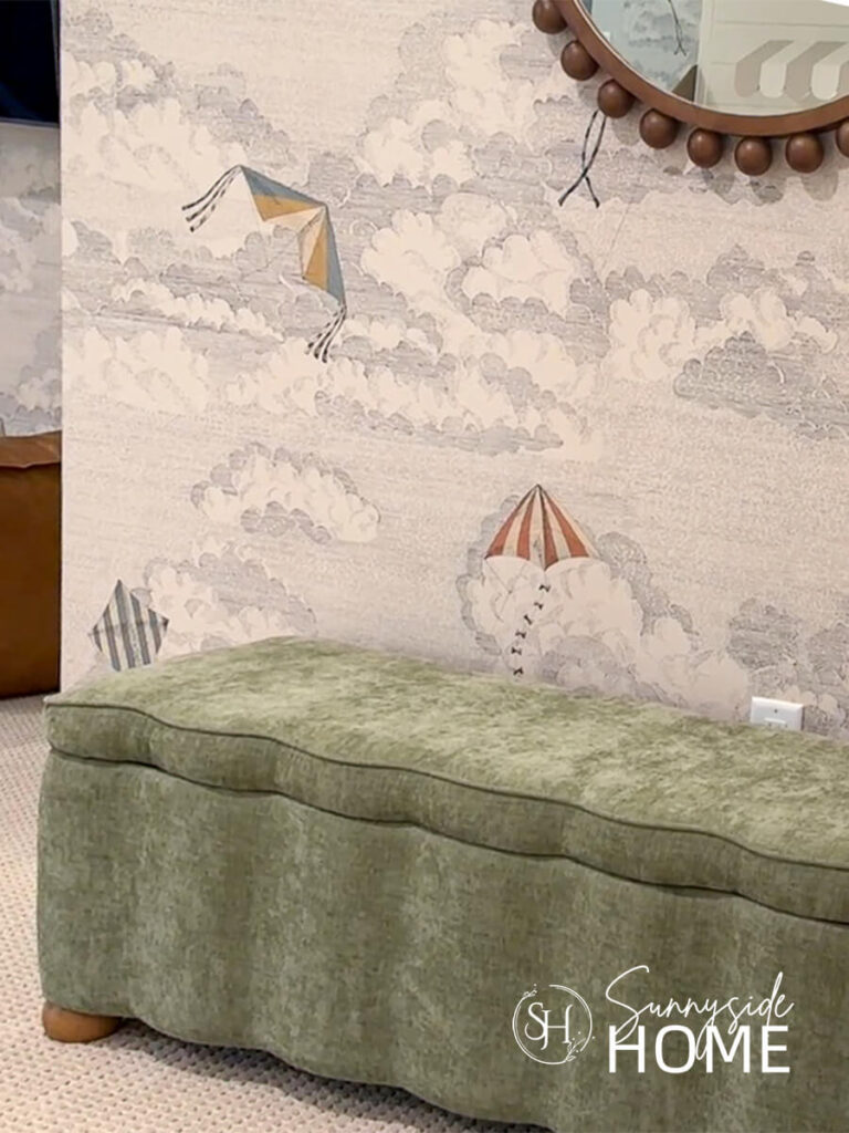 An upholstered scalloped bench serves as toy stoage in this playroom with kite wallpaper and a bead mirror.