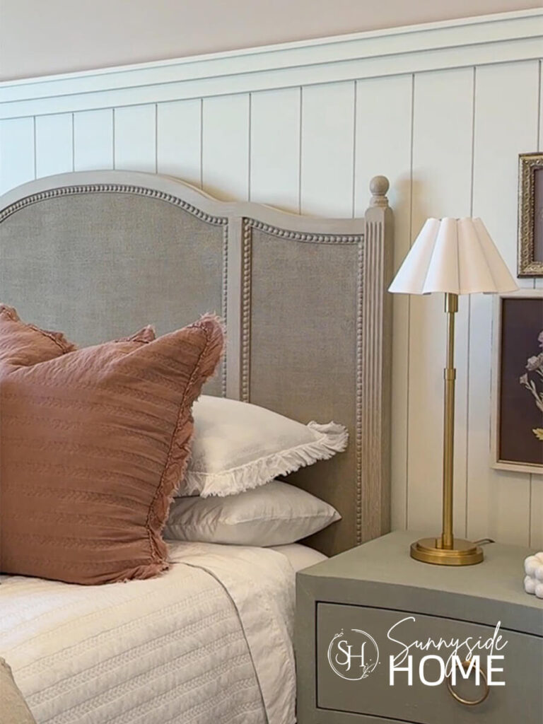 A brass lamp with a scalloped shade on a nightstand in a girls bedroom.