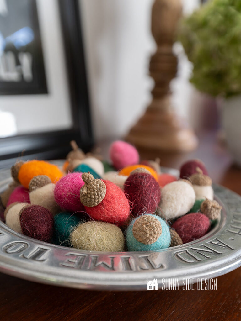 Cozy colorful acorns made with felt balls and real acorn caps, styled in a pewter tray.