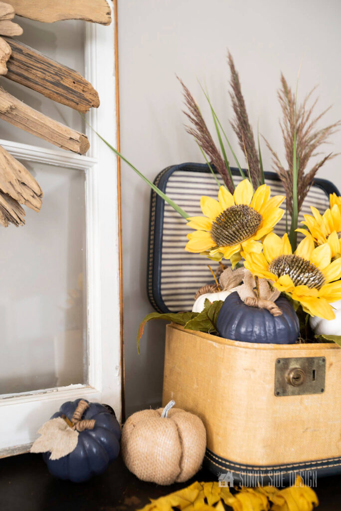 A simple sunflower and pumpkin arrangement in a vintage train case.