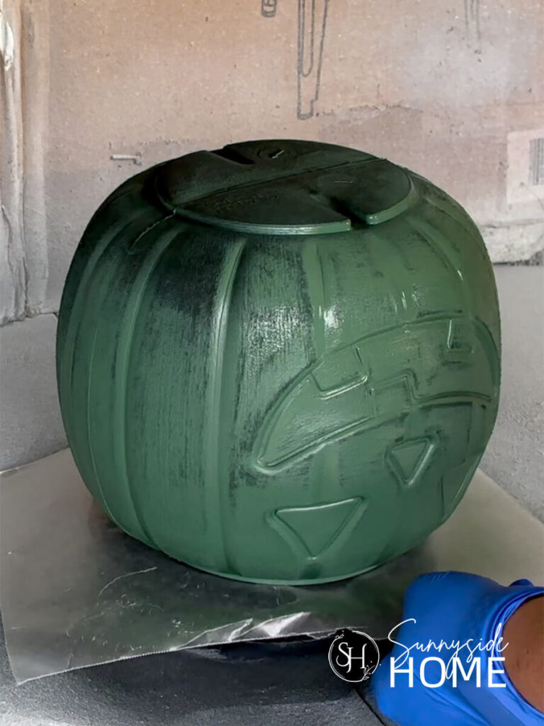 A pumpkin bucket is spray painted green.