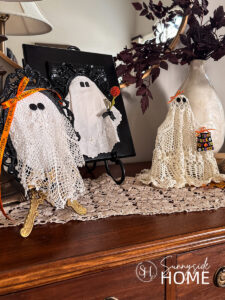 Styled DIY Halloween ghosts made with vintage doily embellished with orange ribbon and a mini trick or treat bag, orange flower and felt.