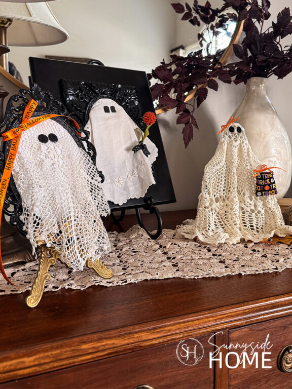 Styled DIY Halloween ghosts made with vintage doily embellished with orange ribbon and a mini trick or treat bag, orange flower and felt.