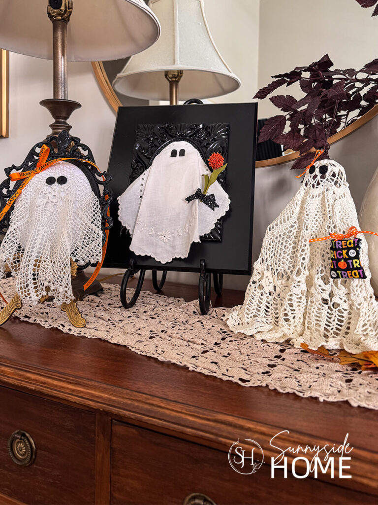 Styled DIY Halloween ghosts made with vintage doily embellished with orange ribbon and a mini trick or treat bag, orange flower and felt.