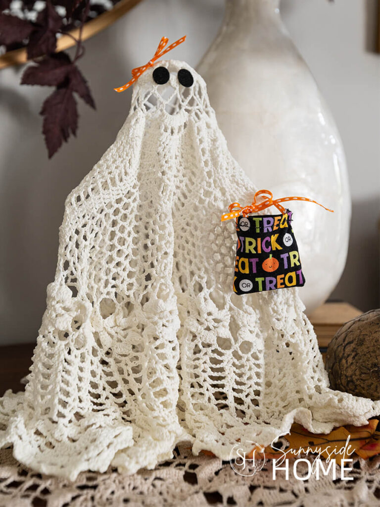 Styled DIY Halloween ghosts made with vintage doily embellished with orange ribbon and a mini trick or treat bag.