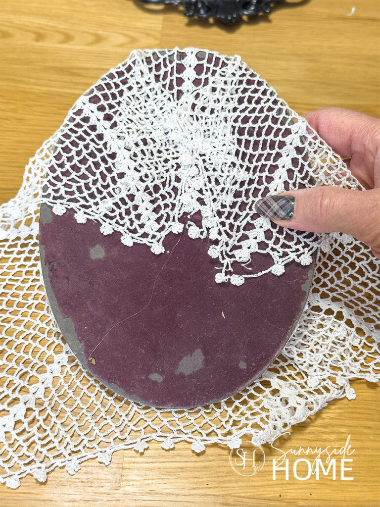 Vintage lace doily secured to the oval frame backing.