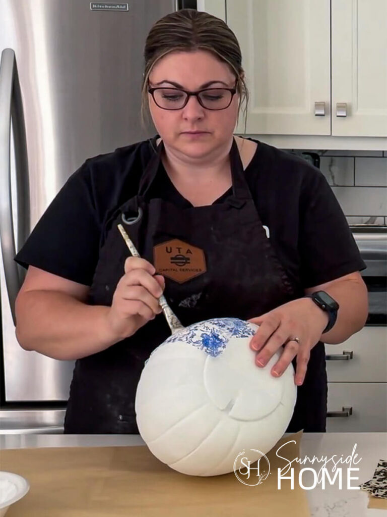 Woman brushed the napkin to the white painted plastic pumpkin.