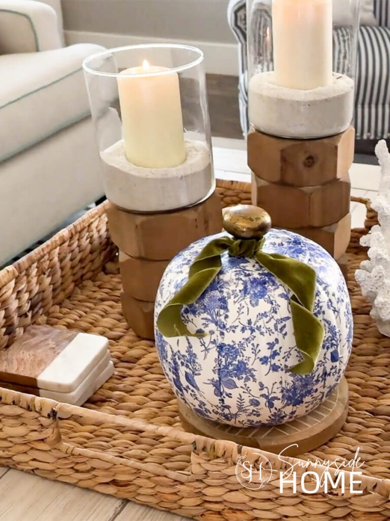 Styled blue and white chinoiserie decoupage pumpkins with pretty floral napkins, embellished with green velvet ribbon, styled in a basket with wood candleholders.