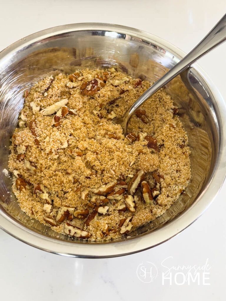 Brown sugar, flour and pecans mixed together in a small stainless steel bowl.