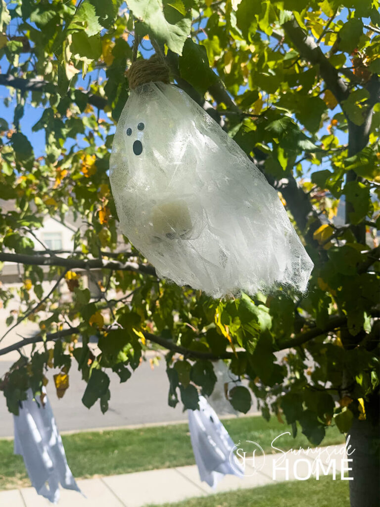 Thrift hair nets are transformed in to lighted flying ghosts and hung from a tree.