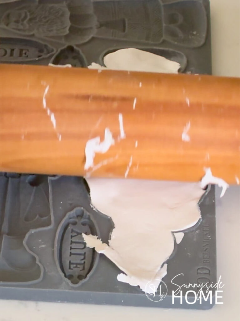 A rolling pin is used to smooth out the clay in the mold.