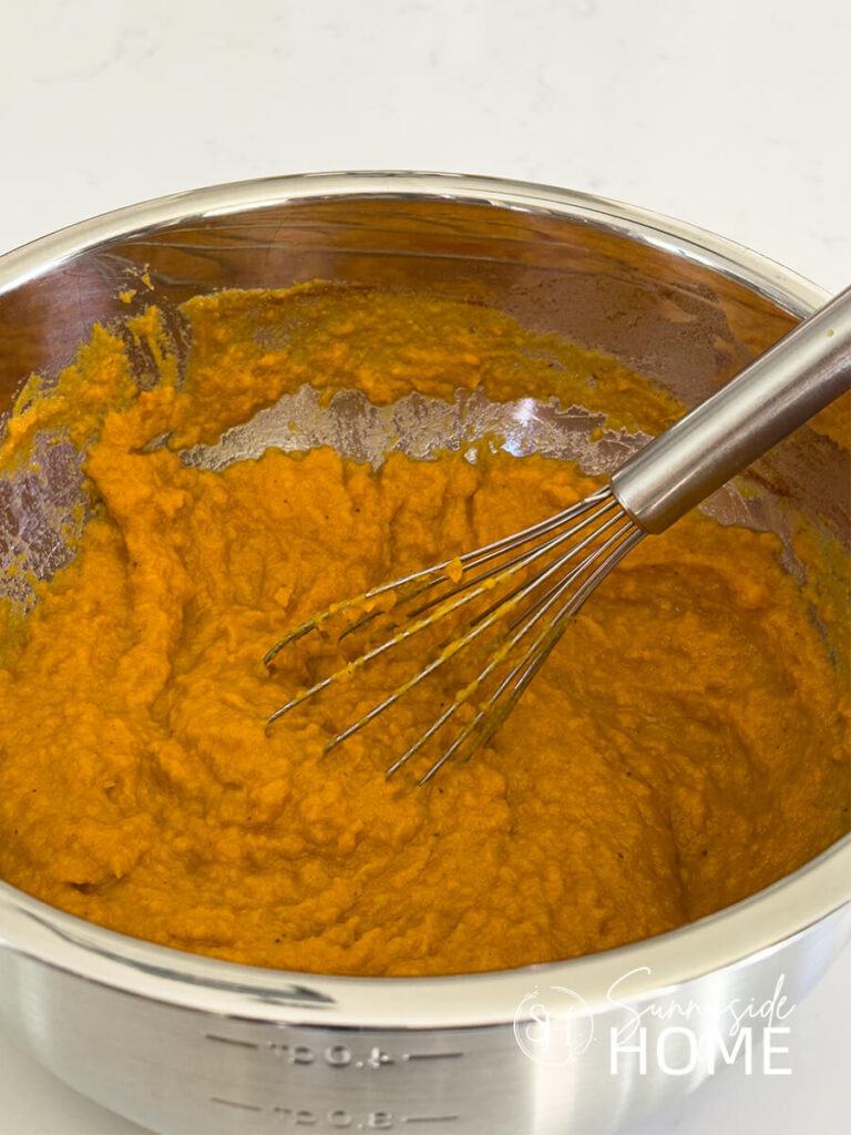 Combined sweet potato mixture in a stainless steel bowl with whisk.