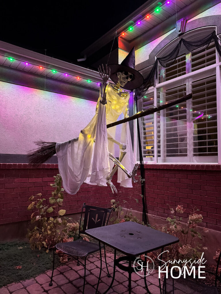 A flying with on her broom is lit up with fairy lights for Halloween.